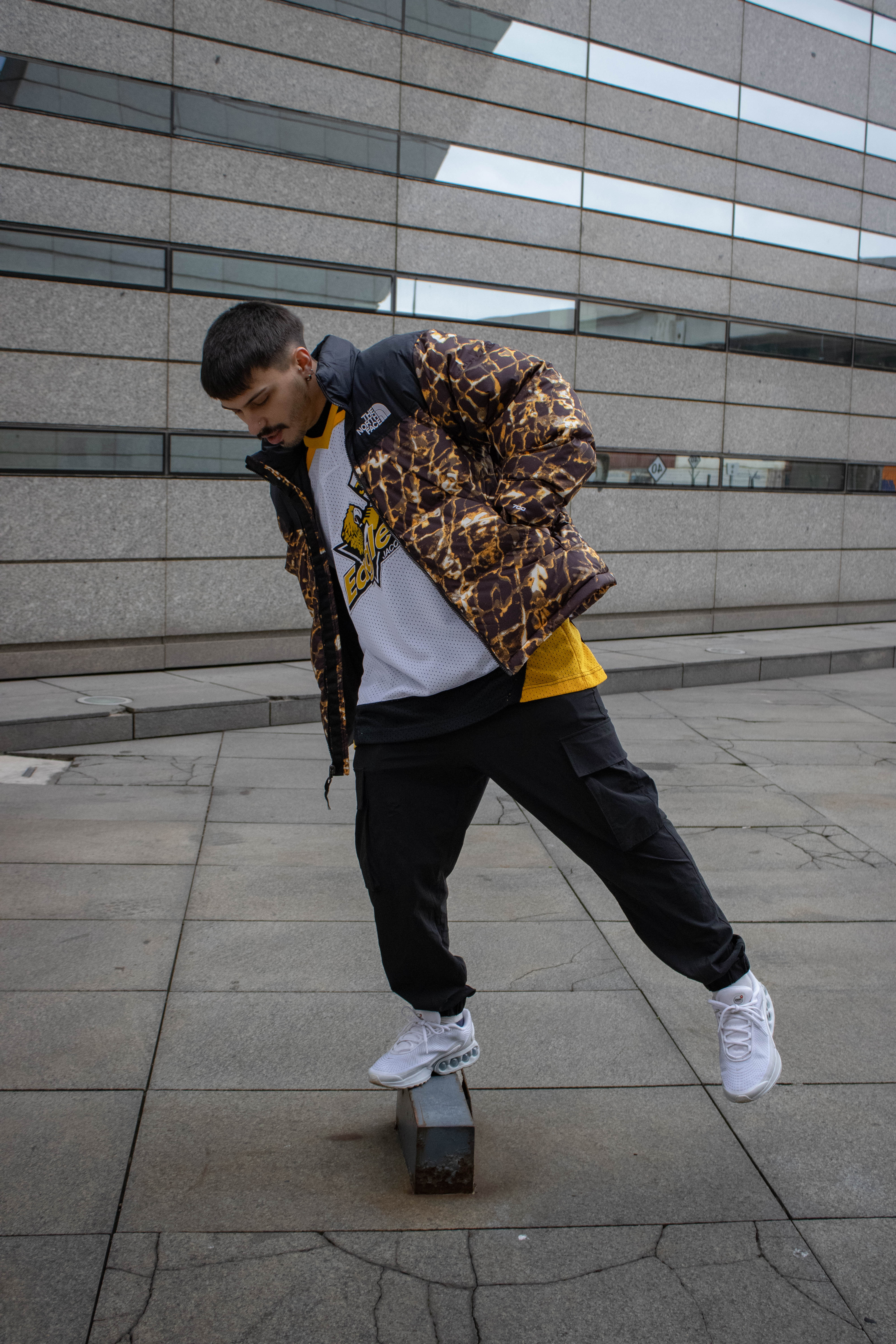 Chico con campera The North Face animal print haciendo un truco de skate — klok curated secondhand