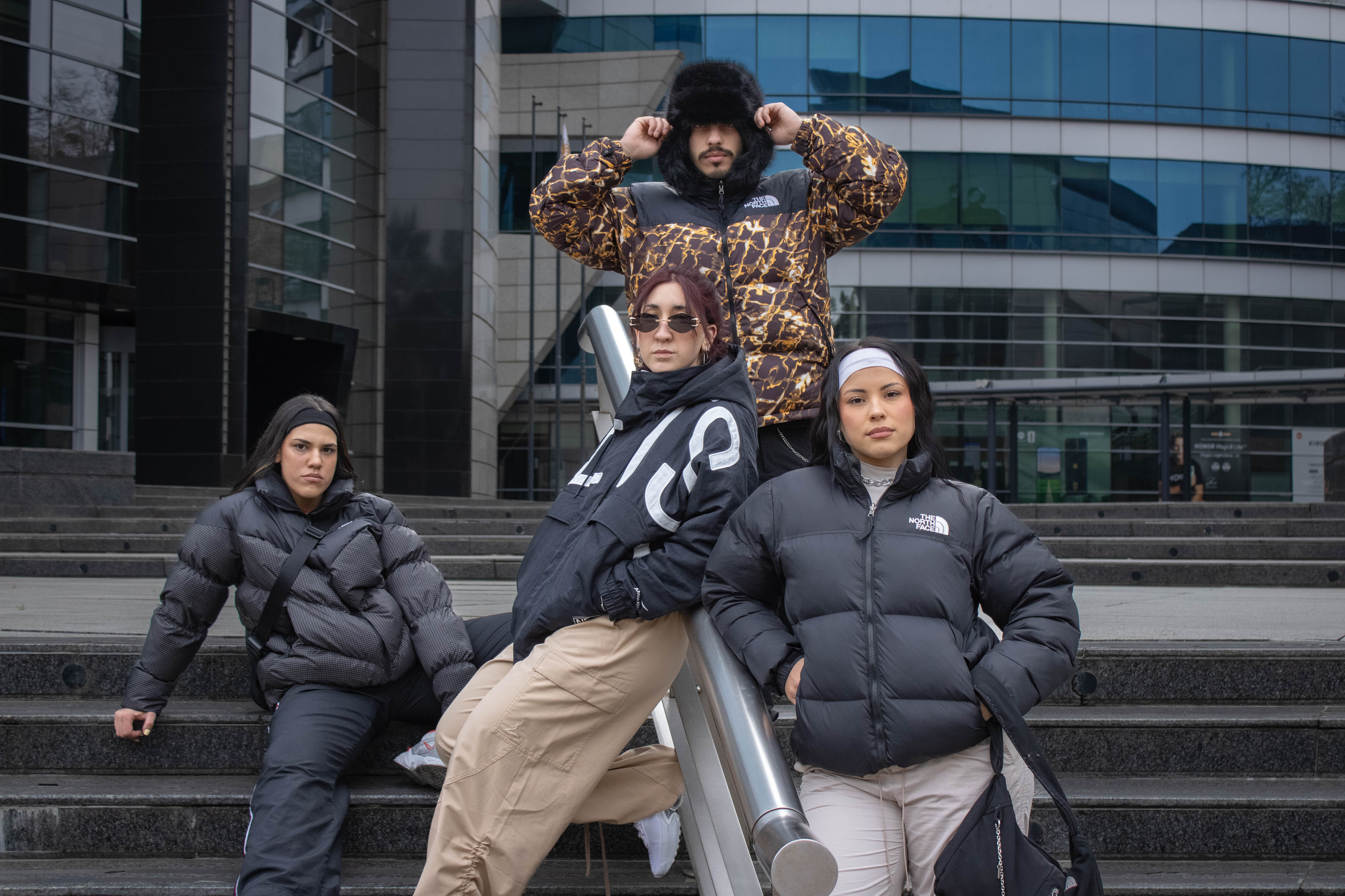 Grupo de amigos con camperas puffer The North Face vintage en una escalinata urbana — klok curated secondhand